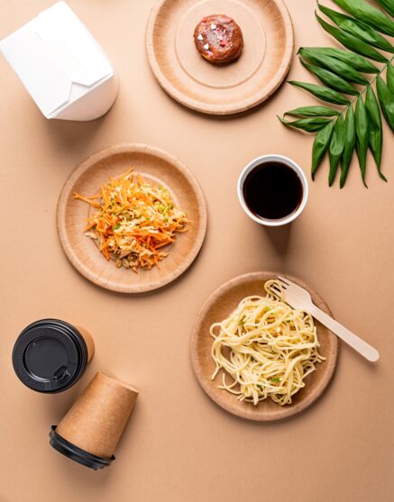 Eco friendly disposable tableware full of food on brown background