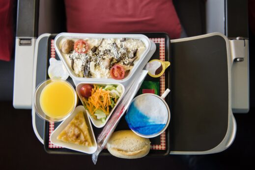 Food served on board of airplane on the table. Fresh meal with salad and orange juice for passenger.